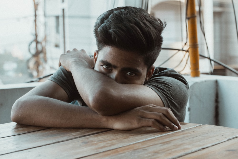 man in black t-shirt leaning on wooden table