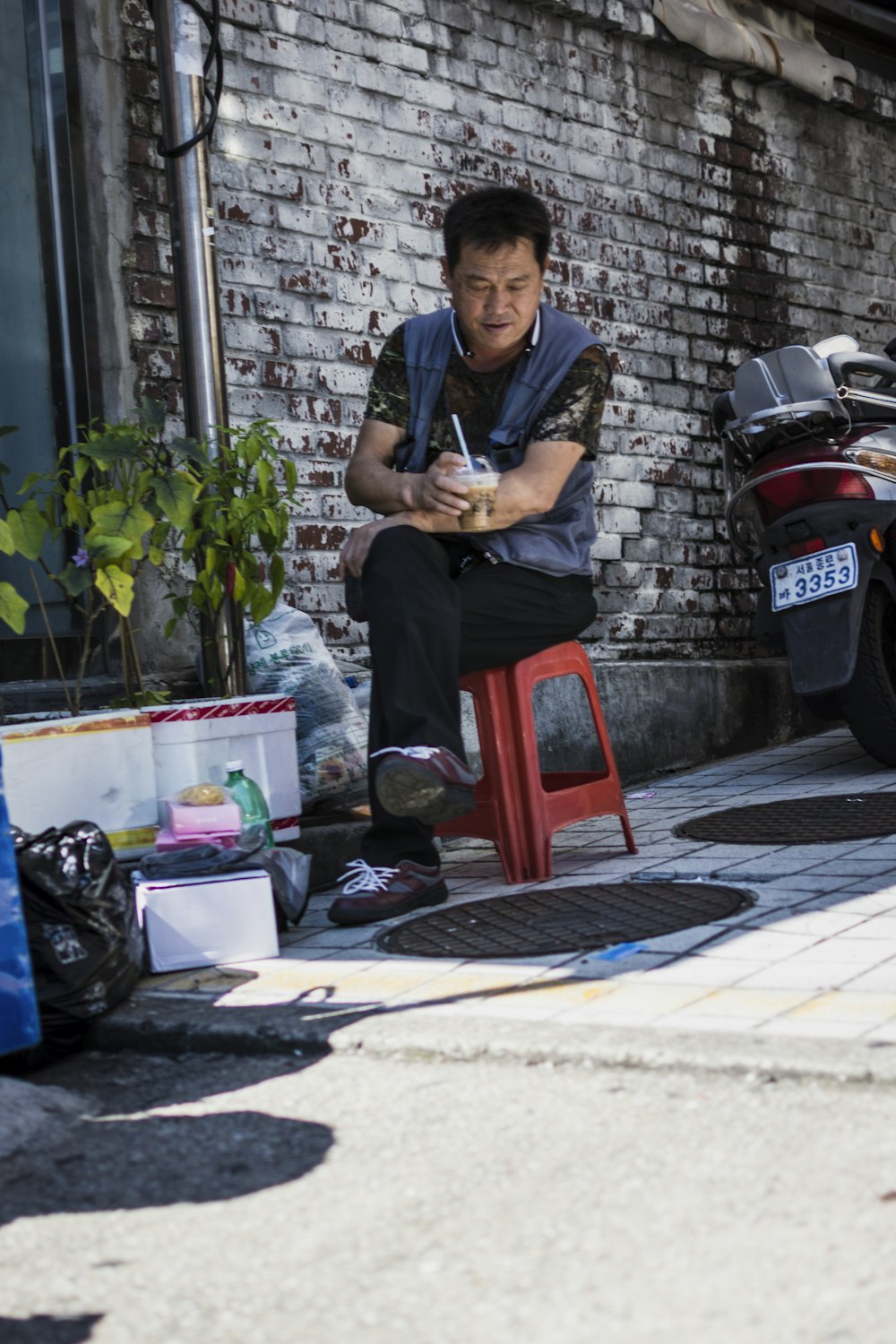 man in blue and black T-shirt sitting on red plastic stool