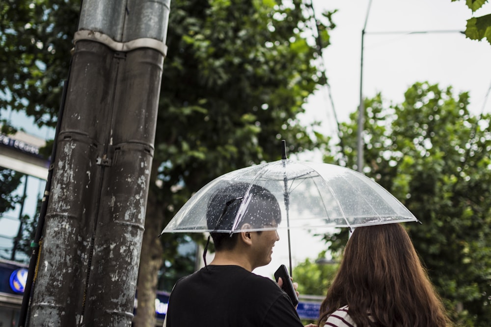 man holding clear umbrella beside woman