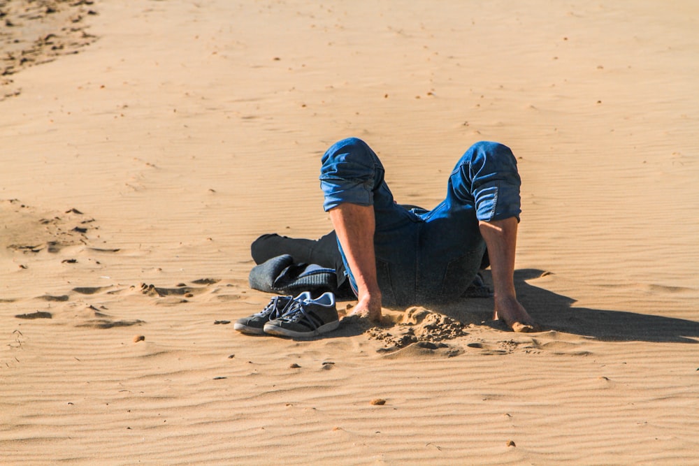 person lying on sand dune