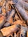 A close-up view of cinnamon bark pieces, displaying textured surfaces and various shades of brown and gray. The pieces are irregularly shaped and densely packed, highlighting the natural, rugged texture.