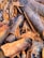 A close-up view of cinnamon bark pieces, displaying textured surfaces and various shades of brown and gray. The pieces are irregularly shaped and densely packed, highlighting the natural, rugged texture.