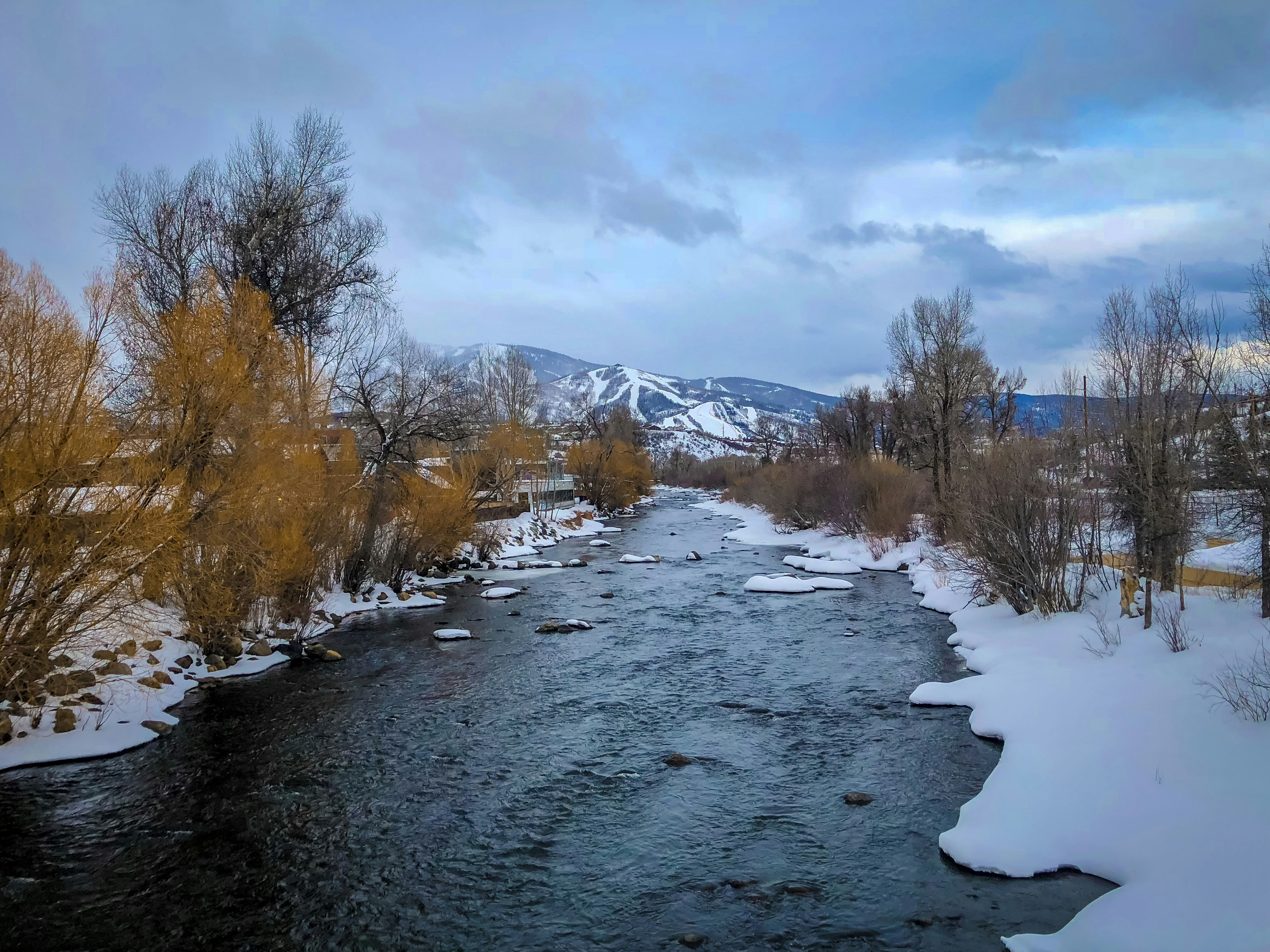 Foto de paisaje de una montaña cubierta de nieve cerca del cuerpo de agua durante el día