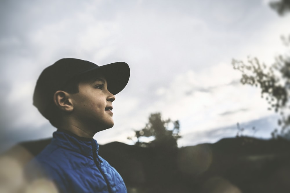 boy in blue jacket and black fitted cap