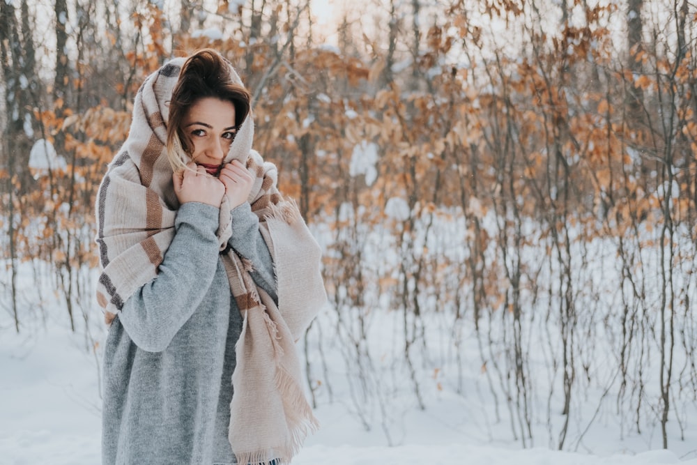 woman wearing grey jacket with brown scarf on snow covered white field during daytime