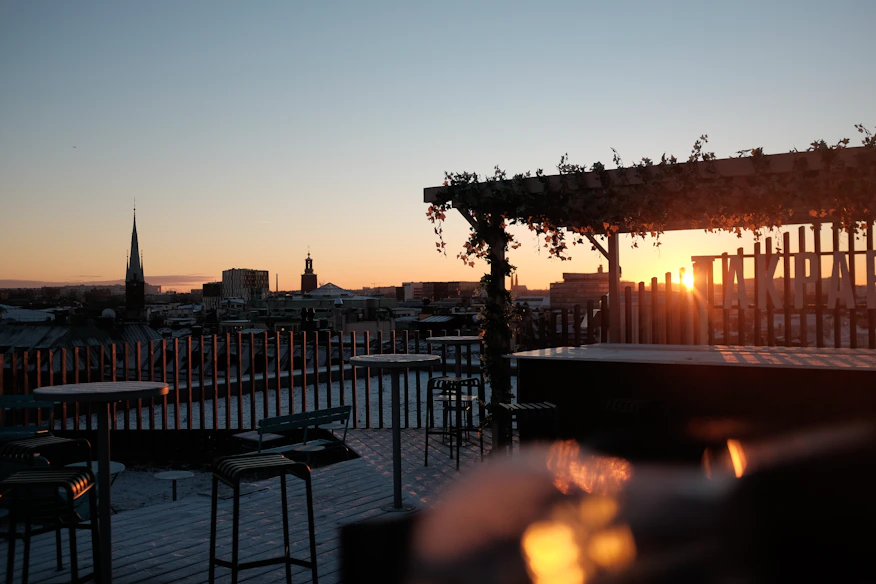 A vibrant rooftop terrace with seating and city views at sunset.