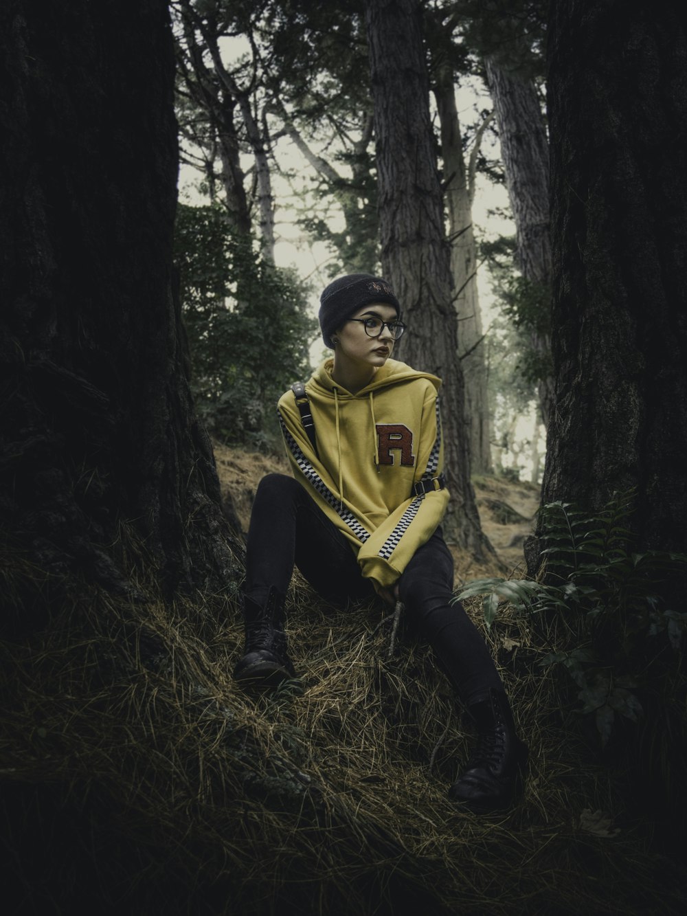 woman wearing yellow pullover hoodie sitting under tree during daytime