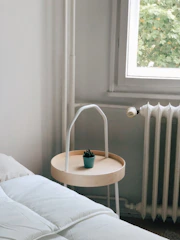 A minimalist bedroom corner with a variety of small potted plants.