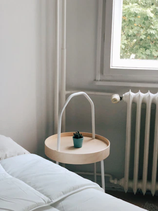 A minimalist bedroom corner with natural linens, a woven basket, and a small potted plant.