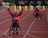 Smiling para-athlete on a handcycle crossing a finish line with cheering crowd.