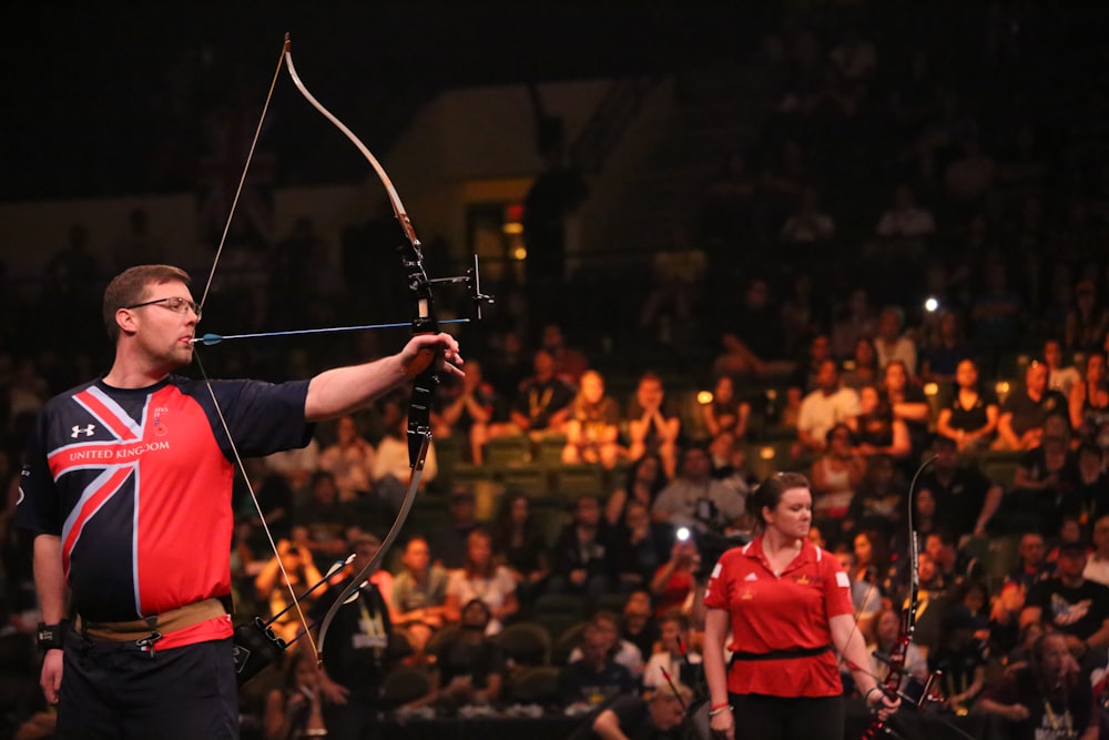 man doing archery near woman holding bow