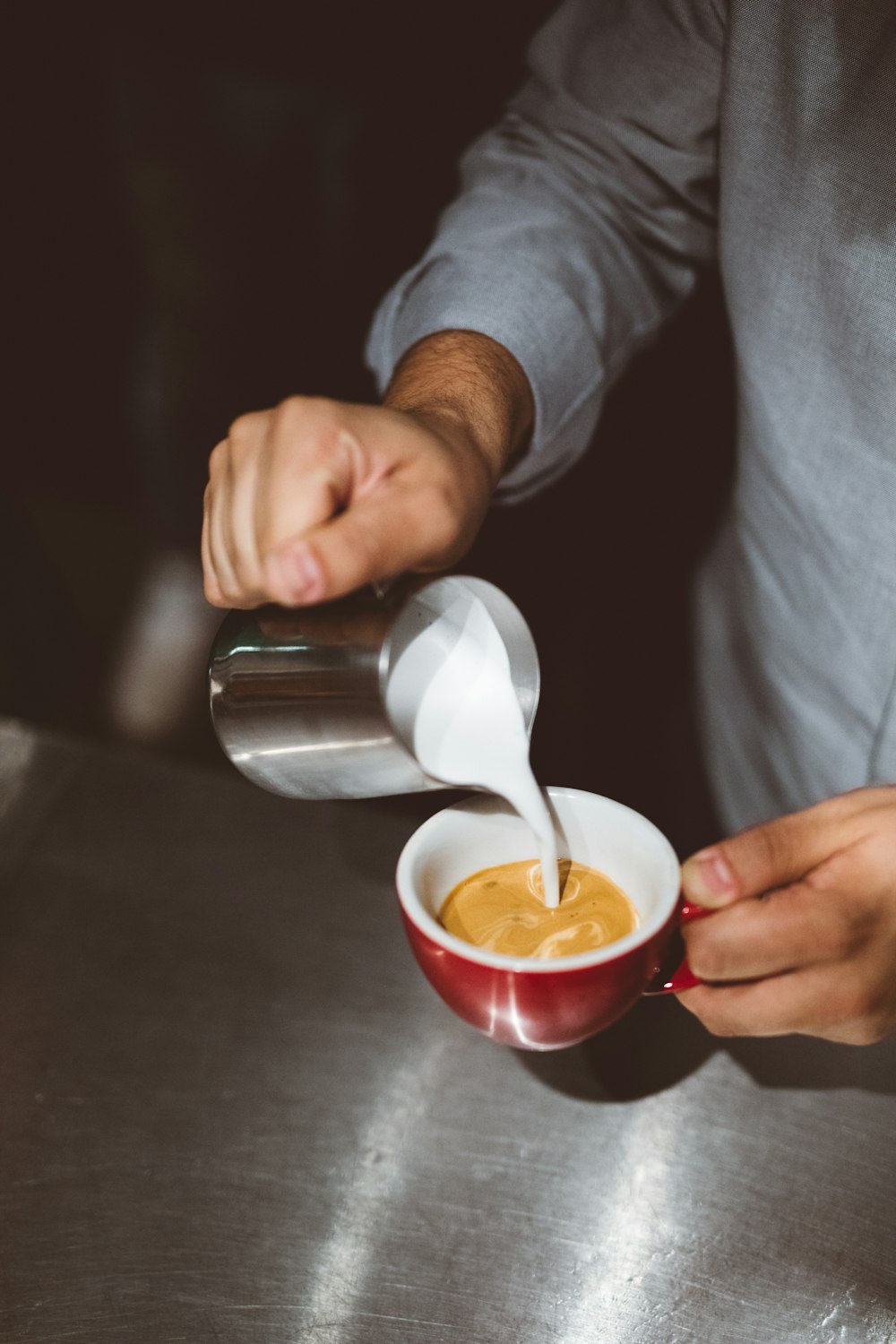 person pouring white liquid in cup