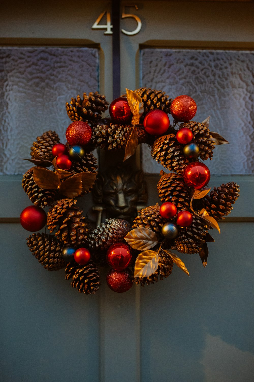 red and brown pine cone wreath on door