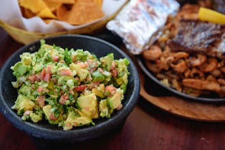 Close-up of a vibrant platter with fresh guacamole, salsa, and handmade tortillas, all onion-free.