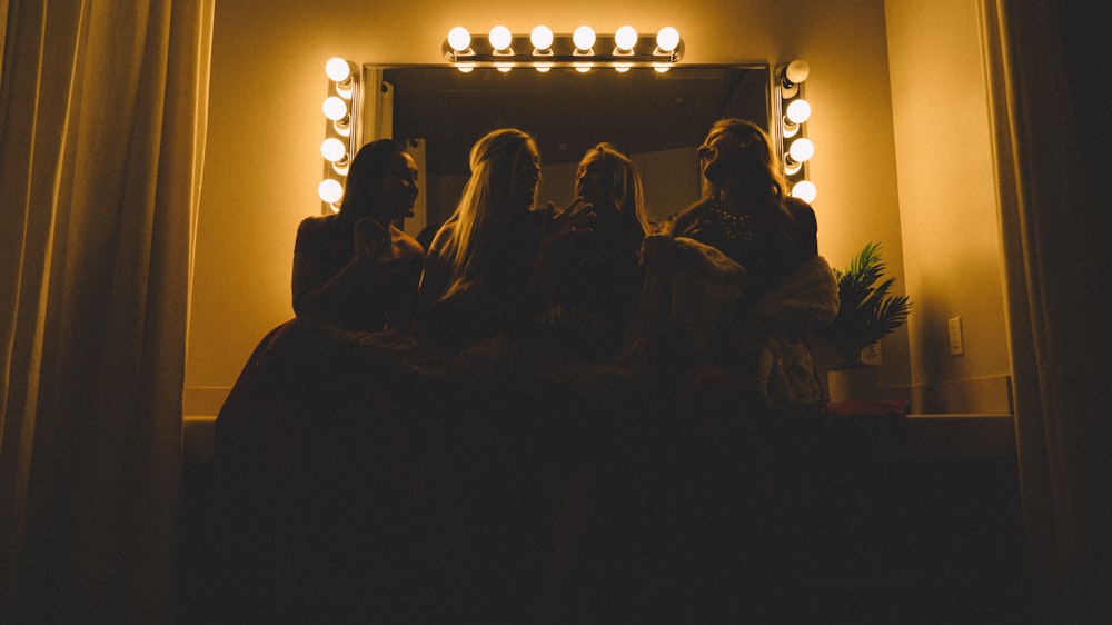 four women sitting infront of vanity table