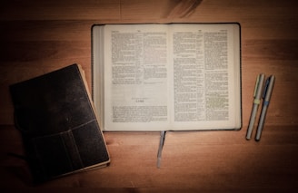 A stack of open books with a pen resting on top.