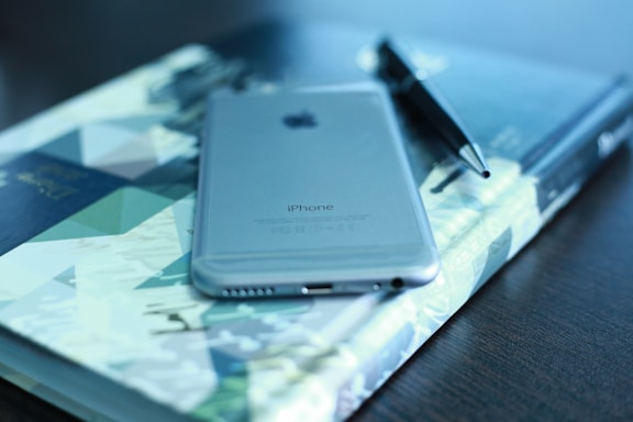 A sleek smartphone on a wooden desk next to a notebook and pen, symbolizing easy communication.