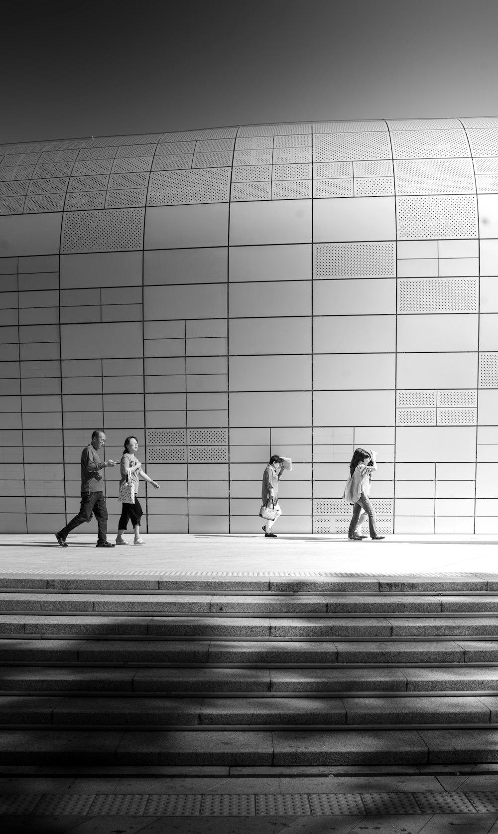 grayscale photo of people walking near building