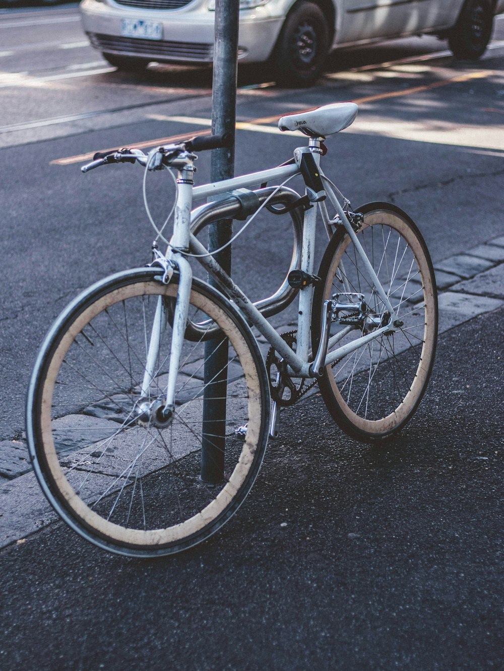 bicycle parked beside post on road side at daytime