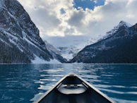 A tranquil lake reflecting snow-capped peaks with a lone canoe drifting quietly.