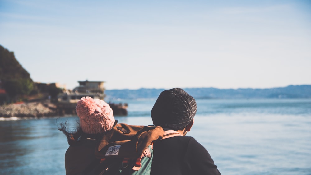 man and woman facing body of water