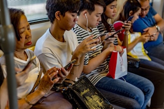 people using smartphones while sitting inside train