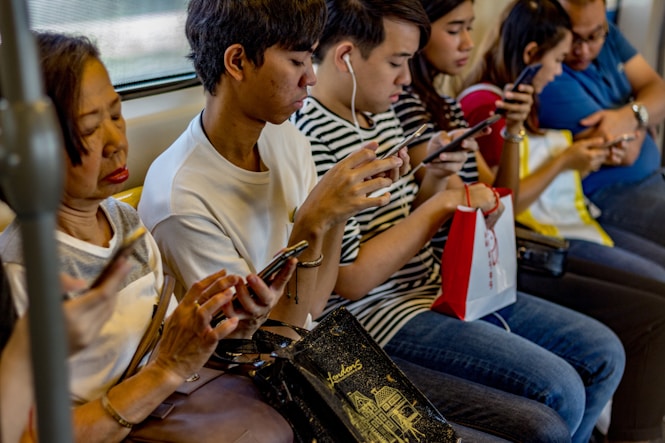 people using smartphones while sitting inside train