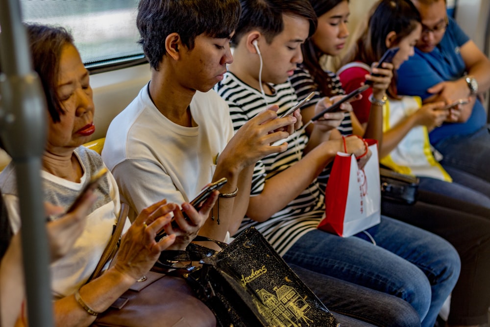people using smartphones while sitting inside train