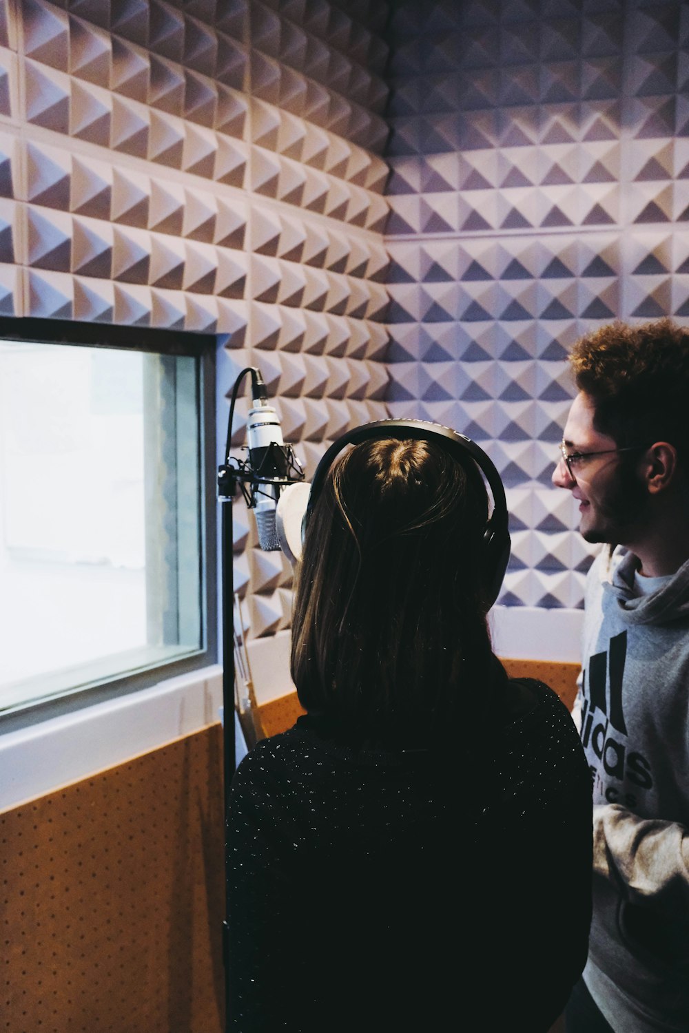 Mujer y hombre cantando en el estudio de grabación