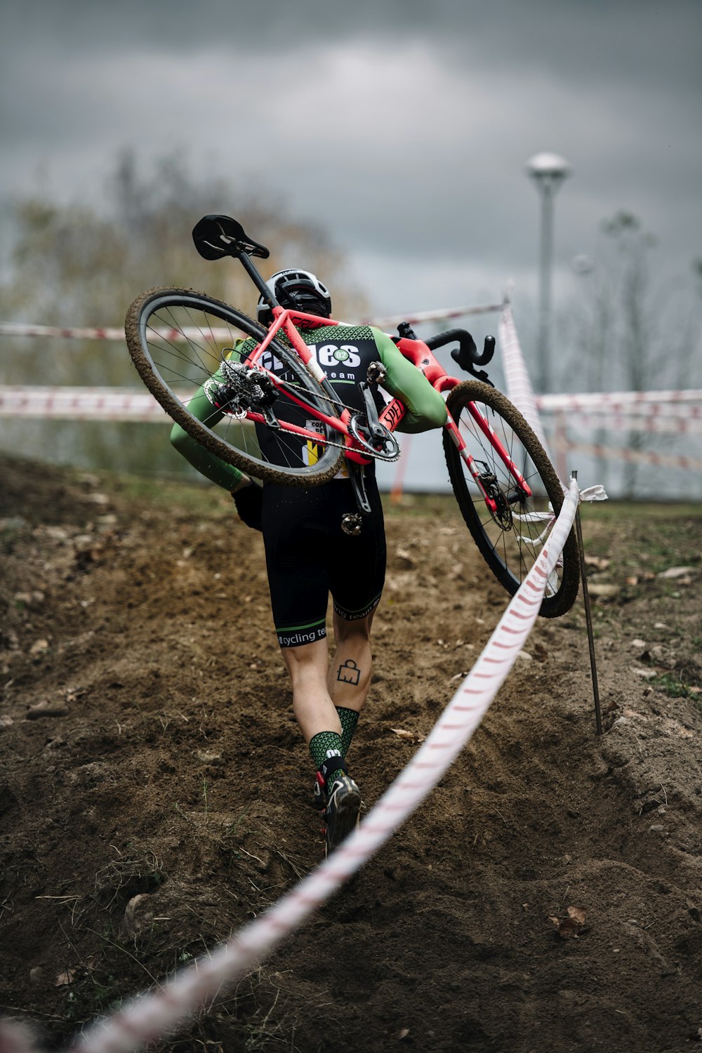 man carrying bike at the rocky road during the race