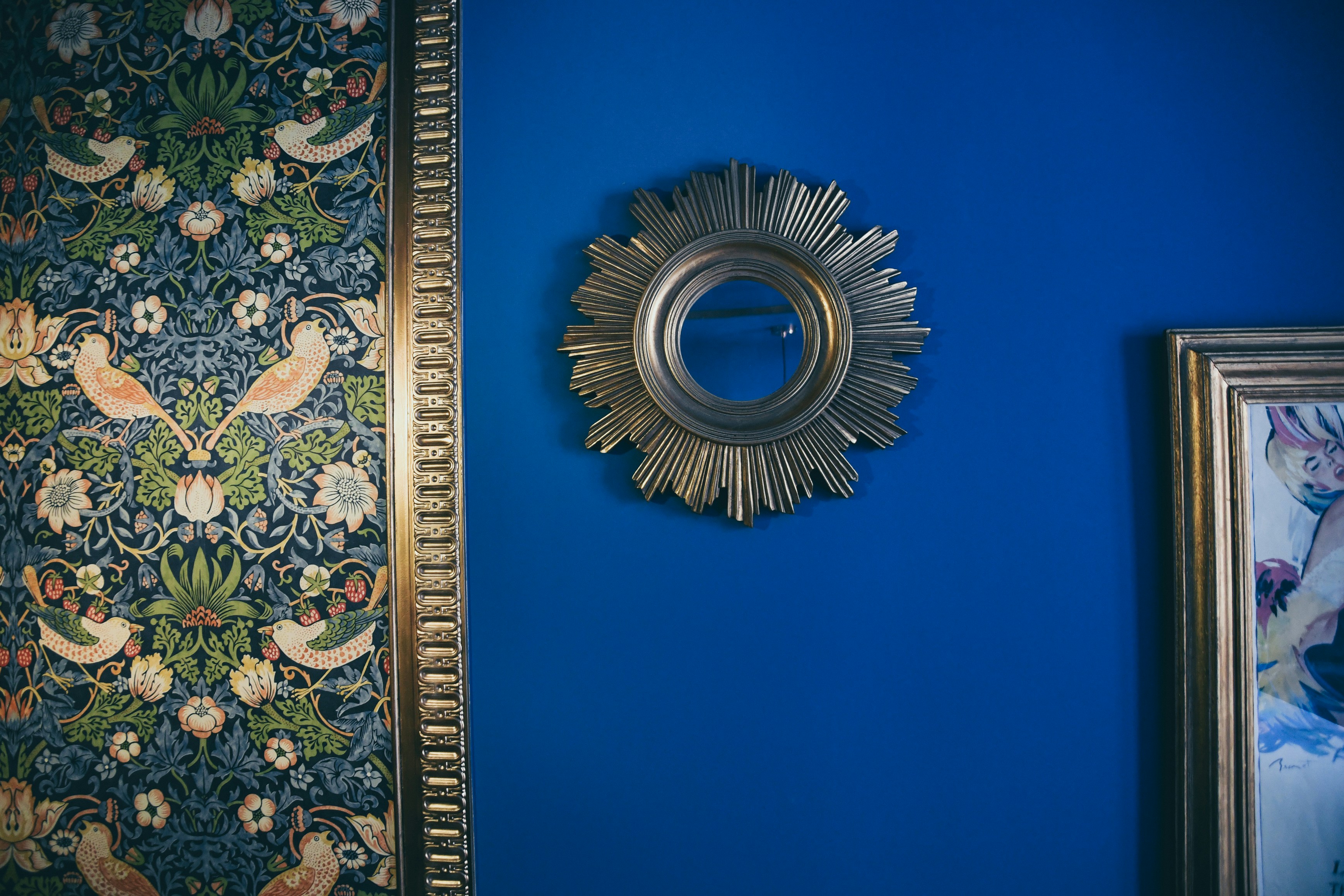 espejo de pared a lado de dos cuadros de arte.