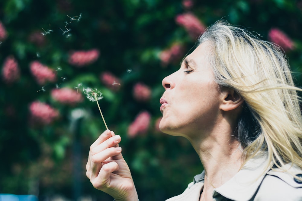 woman blowing dandelion during daytime