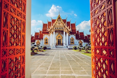 A serene north Indian-style temple entrance adorned with maroon and gold decorations under a clear blue sky.