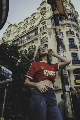Model wearing a vibrant t-shirt from shha knit fashion, standing against a city backdrop.