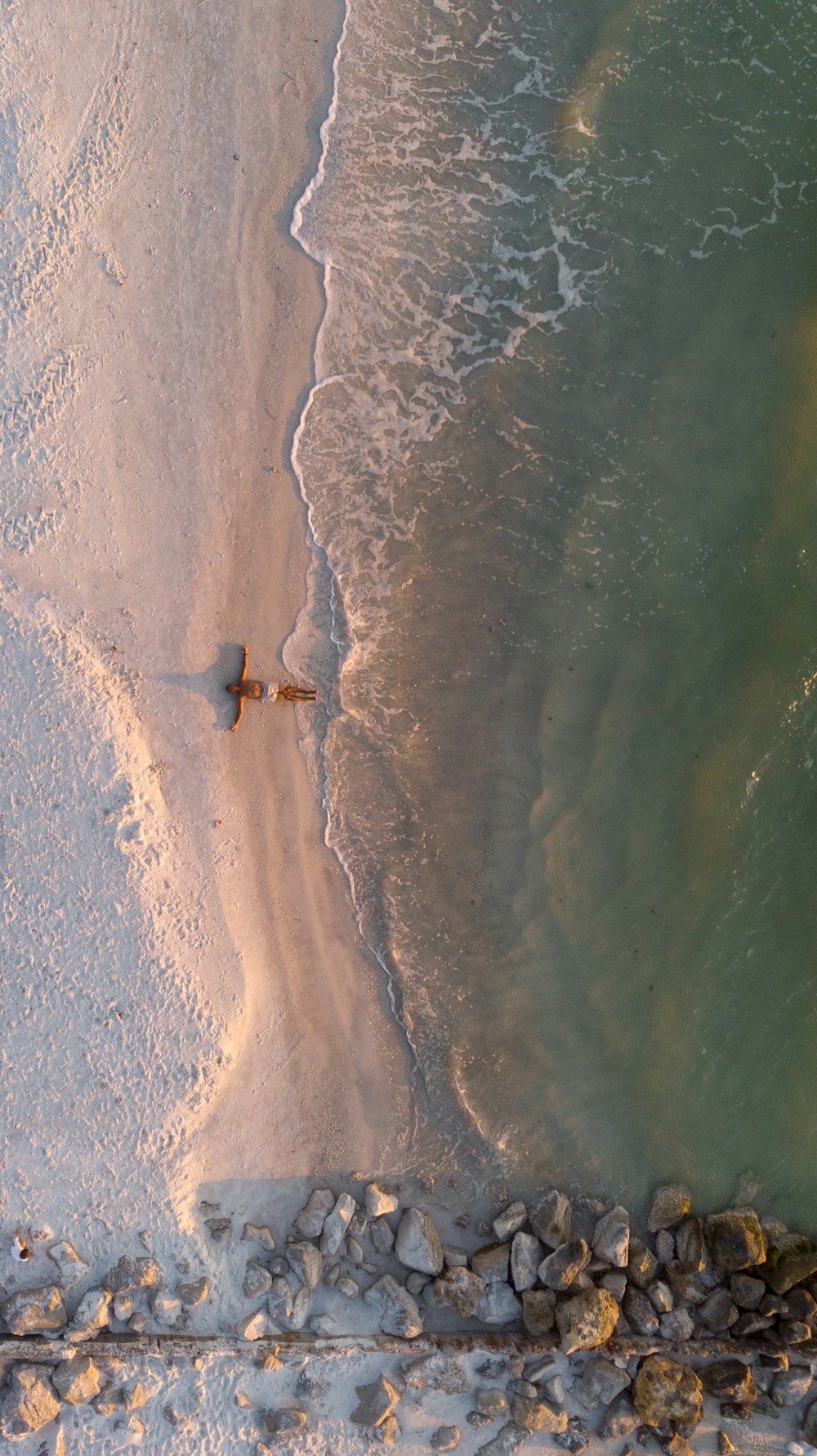 Fotografía aérea de un barco marrón en la orilla del mar cerca de las rocas durante el día