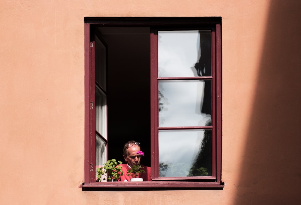 man standing beside window during daytime