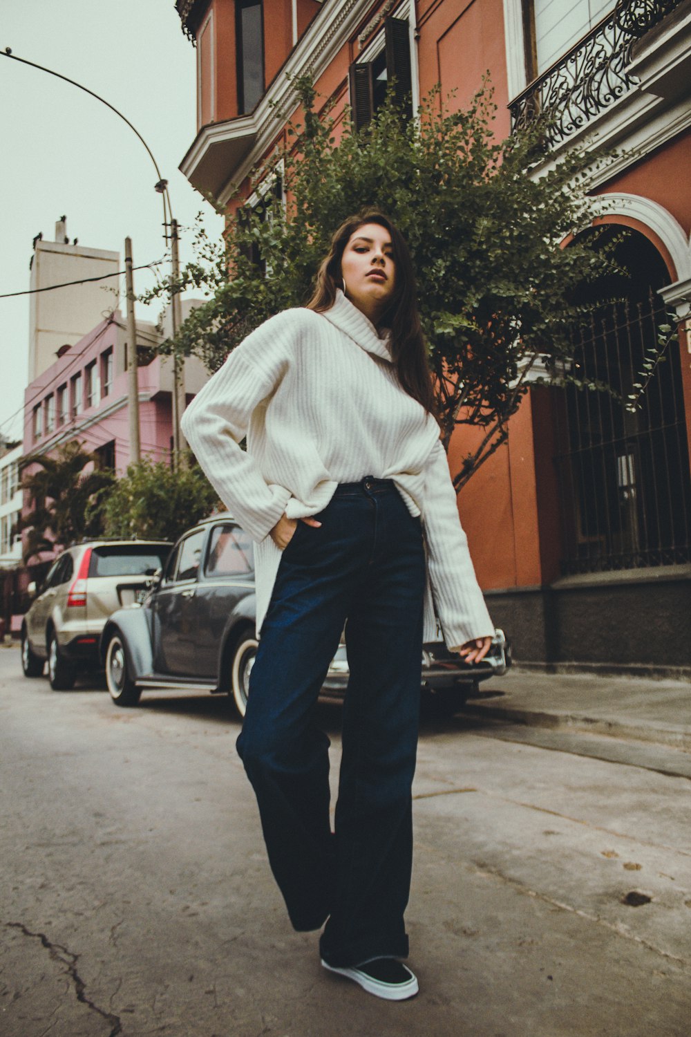 woman in white sweater stands in middle of street