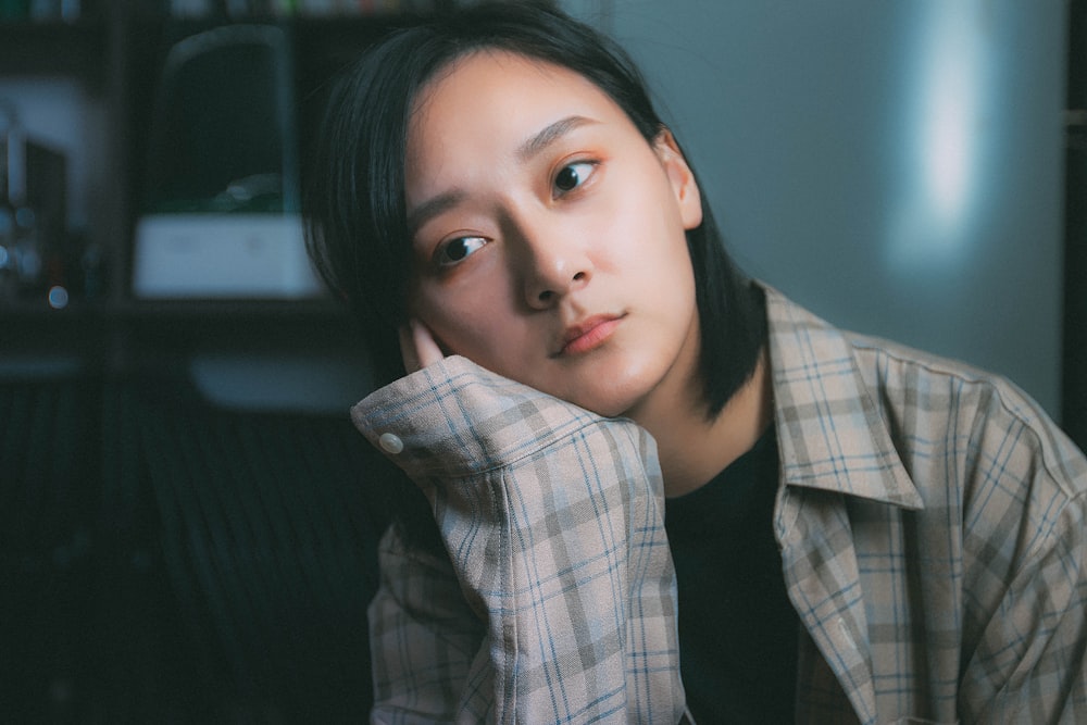 girl wearing brown plaid dress shirt holding cheek