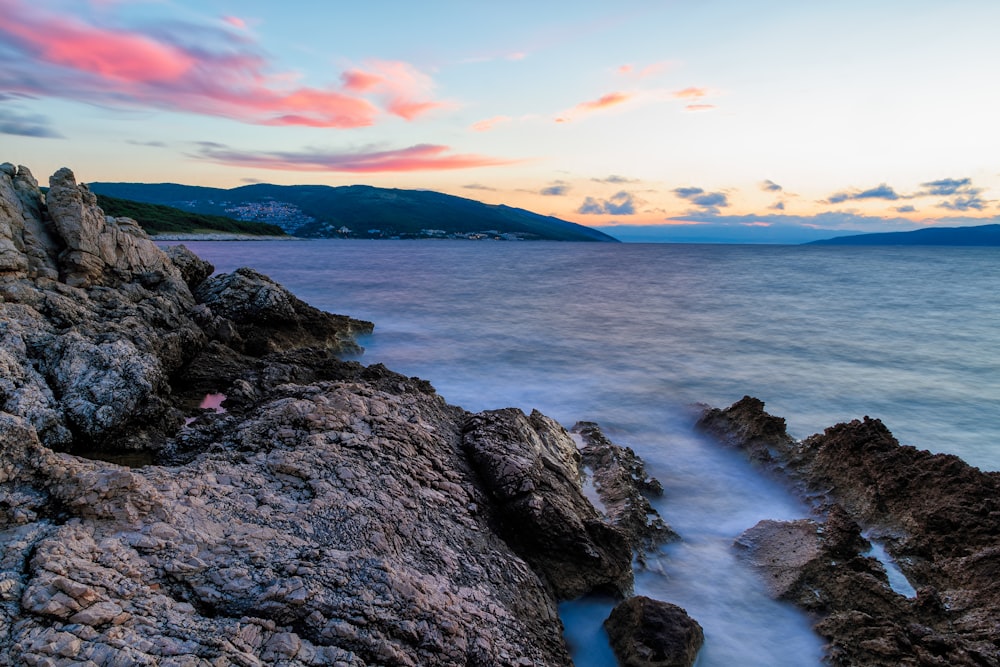 brown rock formations and body of water wallpaper