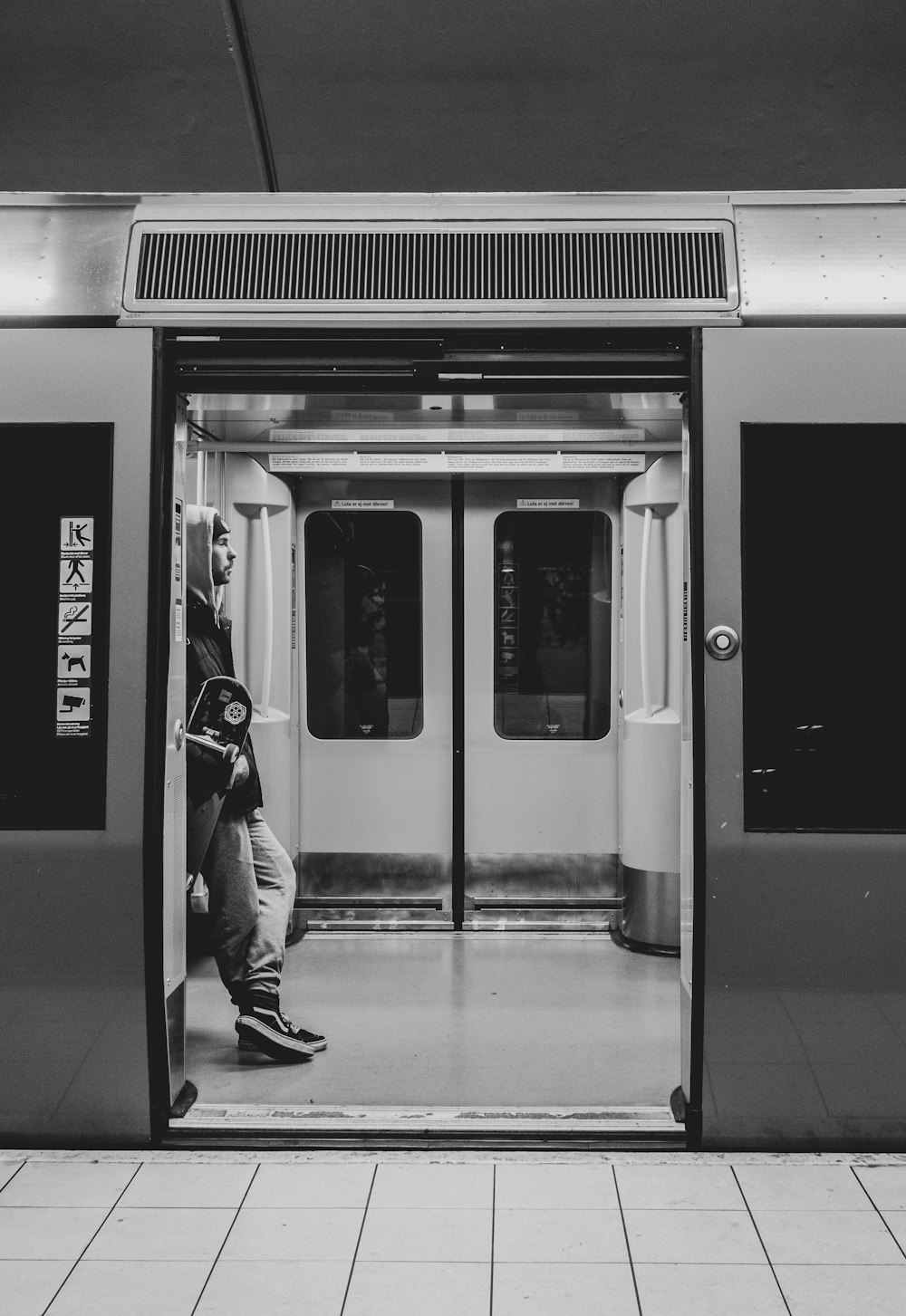 grayscale photo of man standing in train entrance