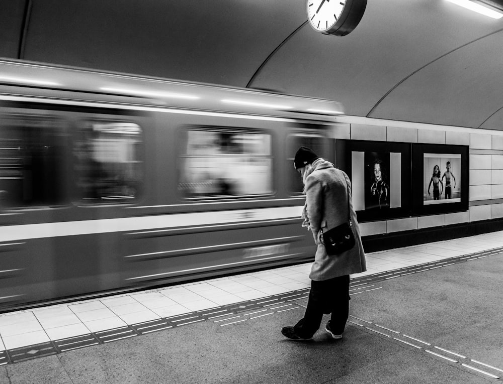 Foto en escala de grises de un hombre en la estación de tren