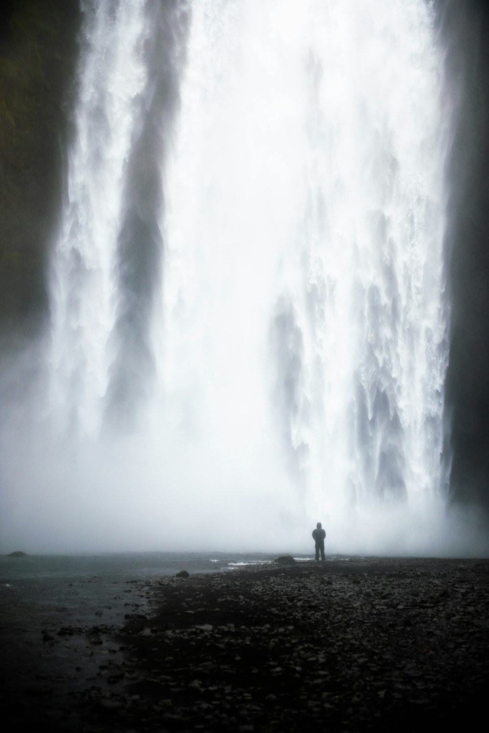 man standing in front of waterfalls