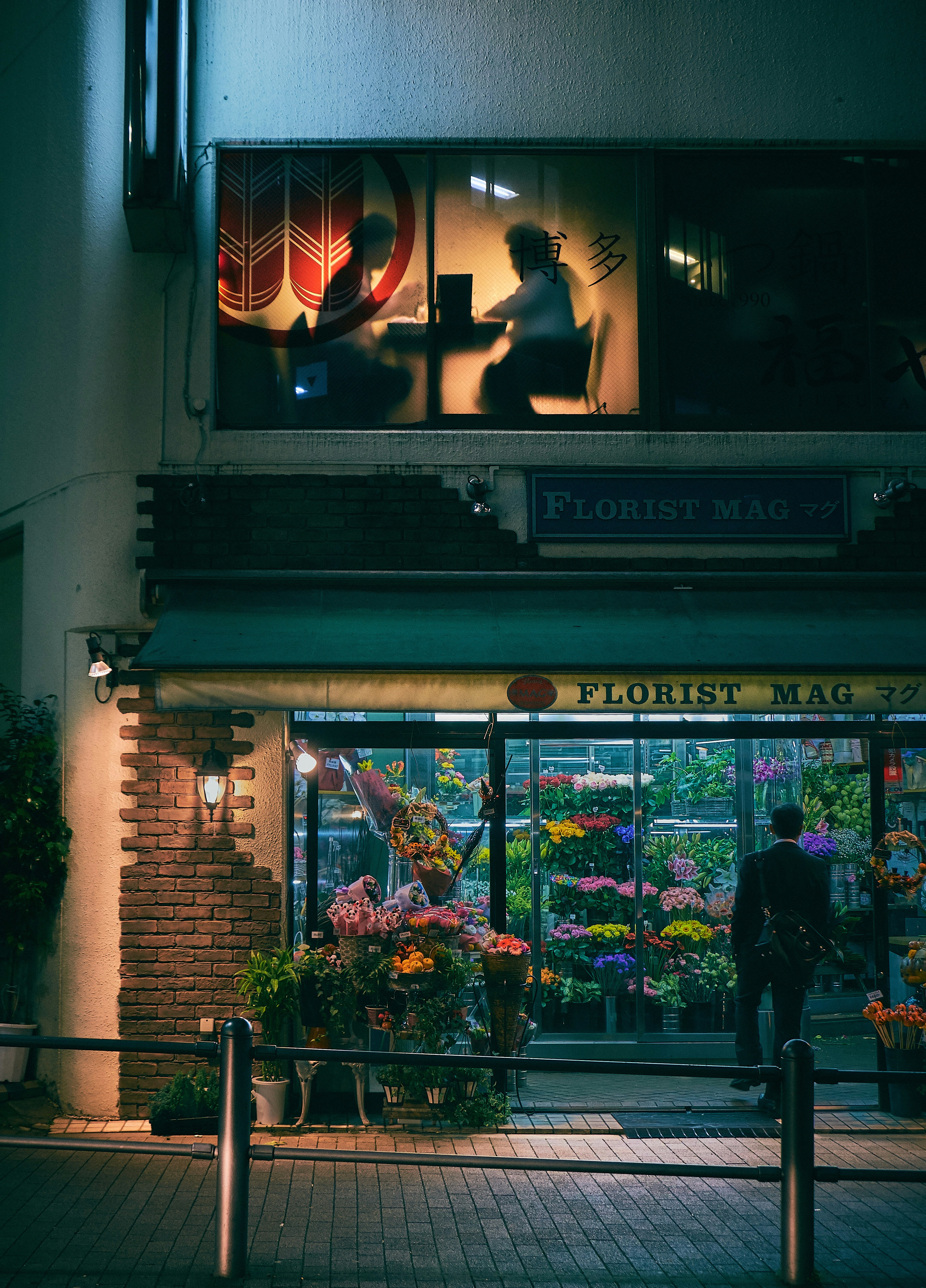 man standing on store front during nighttime