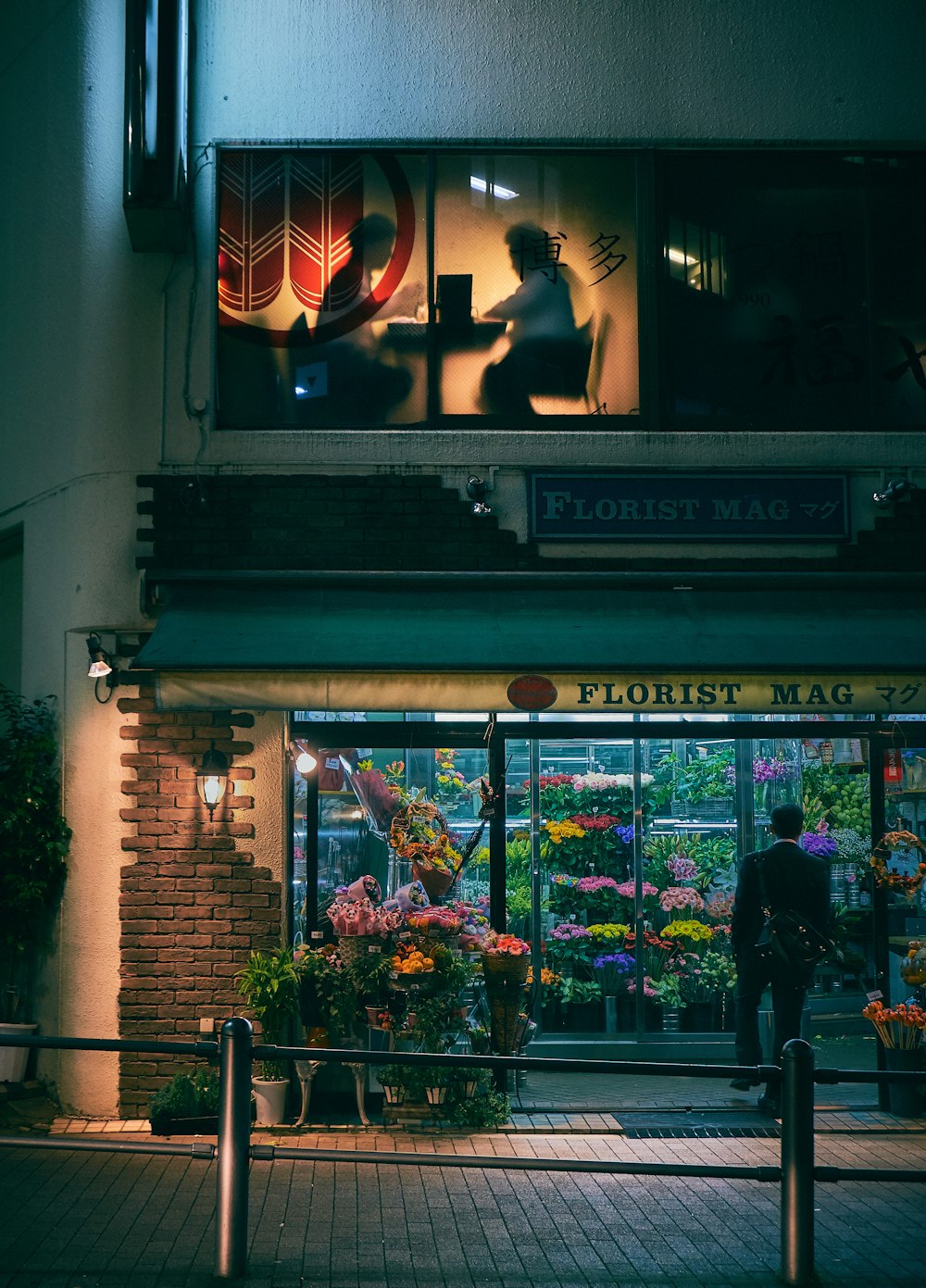man standing on store front during nighttime