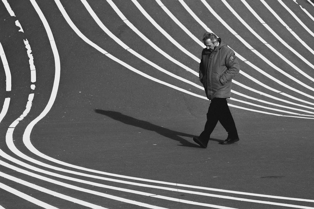 man wearing jacket walking on road