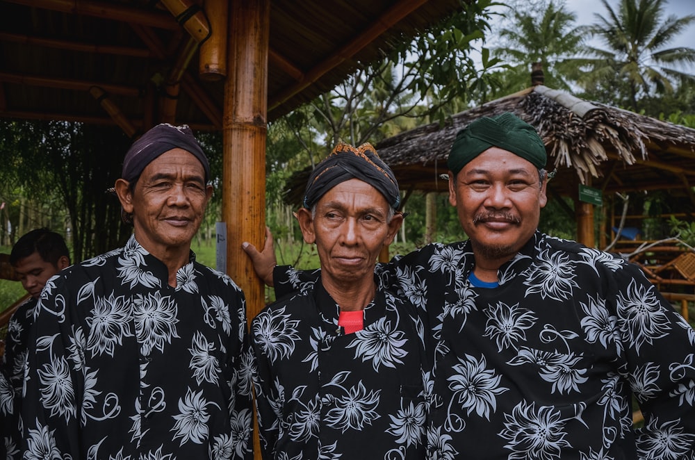 three men wearing black-and-white floral shirts