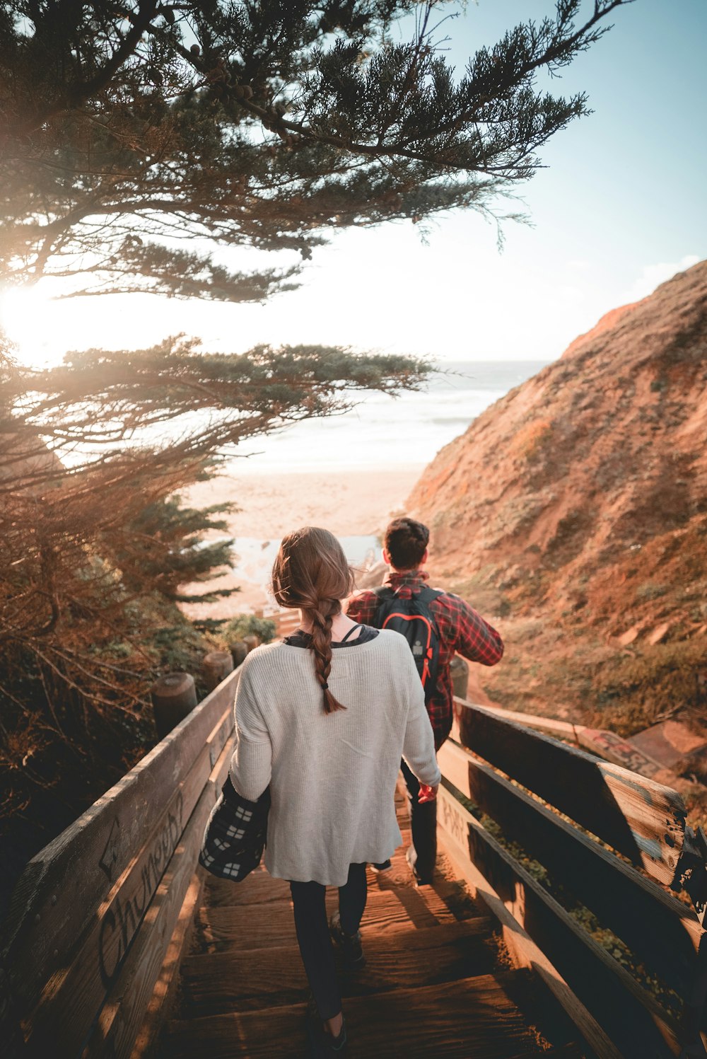 woman and man walking on stair towards beach