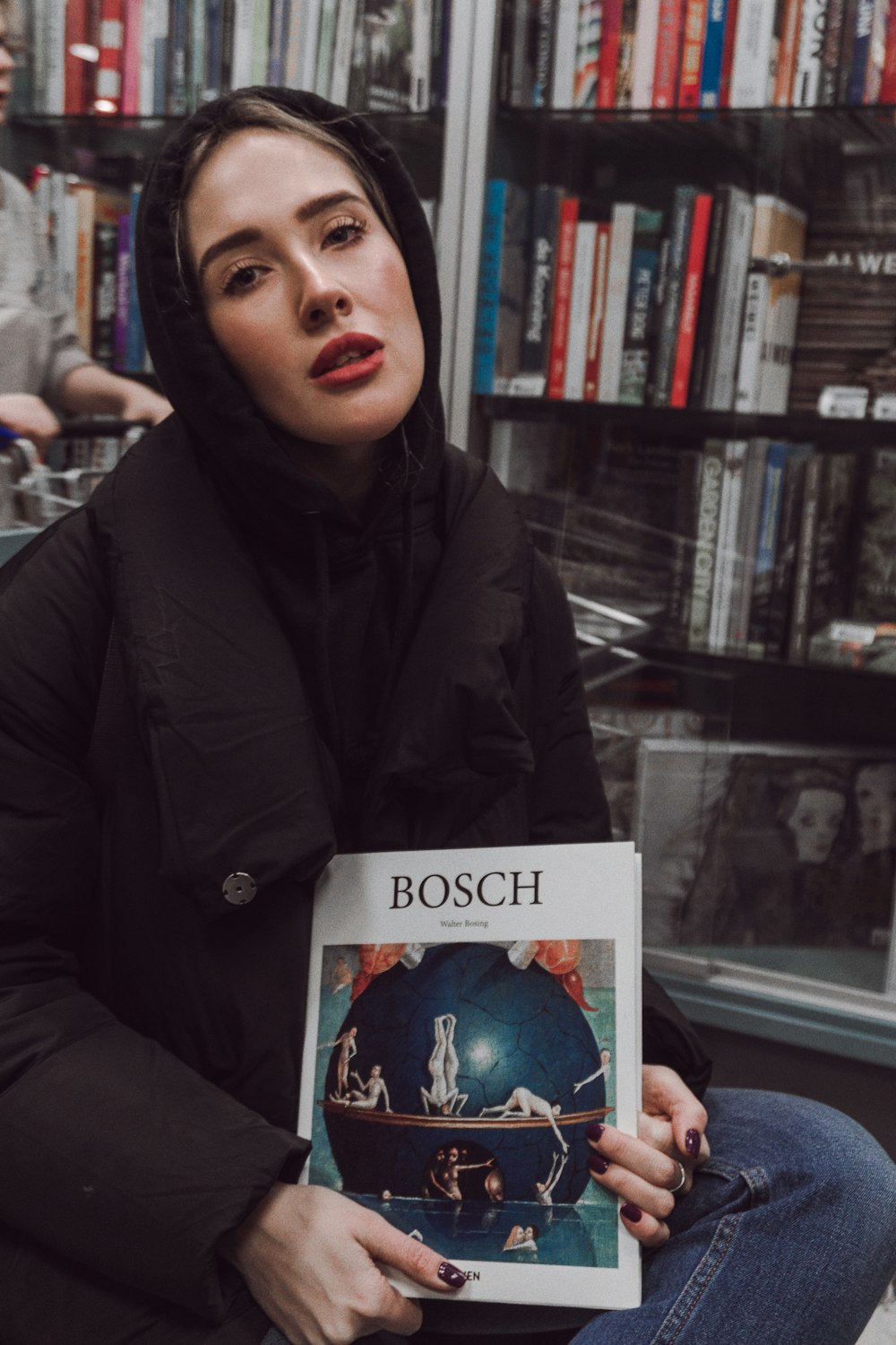 mujer con libro de Bosch dentro de la biblioteca