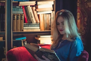 woman sitting on chair while reading book