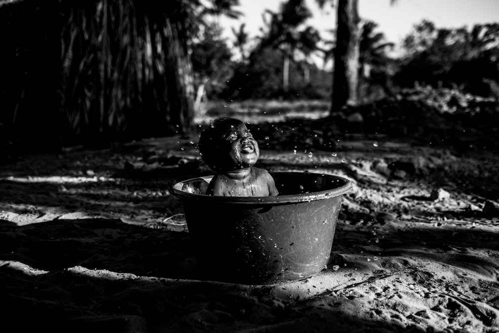 topless baby smiling and sitting on pail